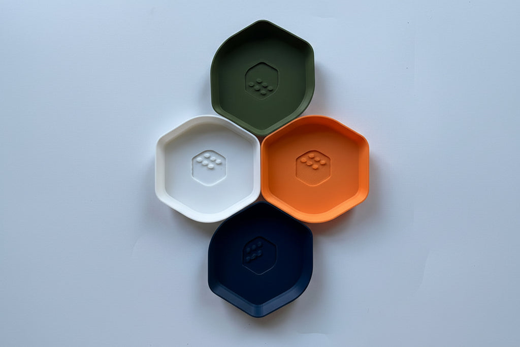 Four hexagonal containers in orange, green, white, and navy on a light gray background.