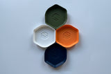 Four hexagonal containers in orange, green, white, and navy on a light gray background.